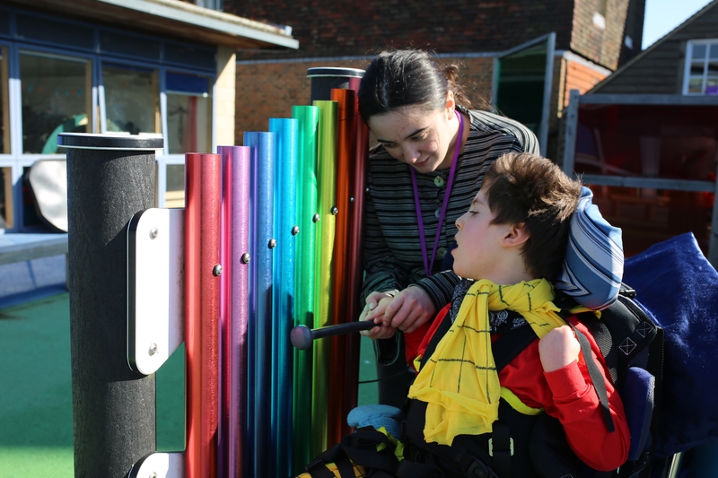 A young person and an adult are looking at a colourful outdoor fence