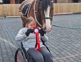 Young person in a wheelchair with horse and rosette