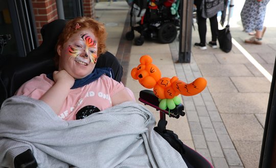 Women in a wheel chair with tiger face paint and balloon tiger