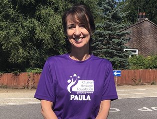 Paula standing up outside and smiling, wearing a purple t-shirt