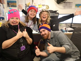 Team mates wearing woolly hats and smiling